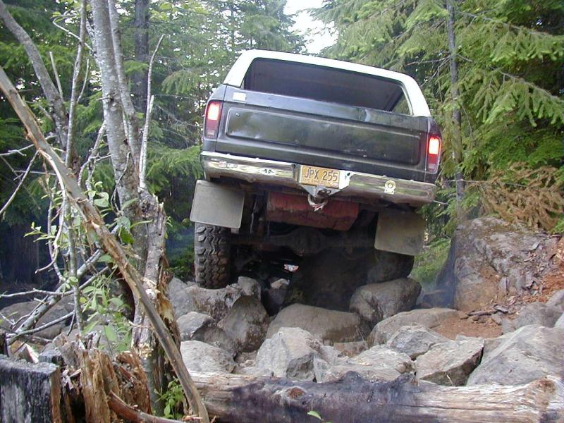 Dark green 1978 Ford Bronco with a white top, navigating a rocky trail
