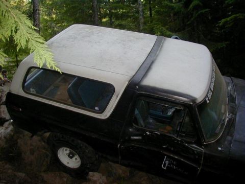 1978 Ford Bronco - This Ford Bronco is parked off-road on a rocky surface, surrounded by trees.