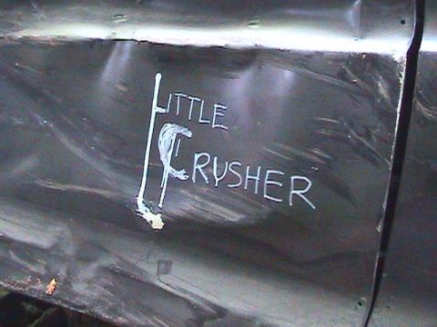1978 Ford Bronco - A dark vehicle's side panel displays the hand-painted name 'LITTLE CRUSHER' amidst signs of wear and tear.