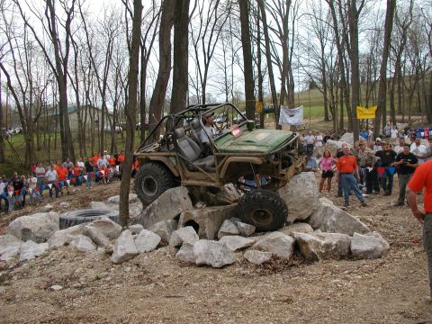 1992 Ford Bronco - An off-road vehicle attempts to traverse a rocky obstacle course with spectators watching.