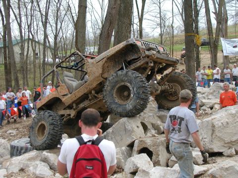 1992 Ford Bronco - A heavily modified off-road vehicle navigates a challenging rocky obstacle course with onlookers present.
