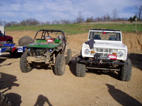 1992 Ford Bronco - Two modified off-road vehicles, a white Ford Bronco and a green Suzuki Samurai, are parked side-by-side.