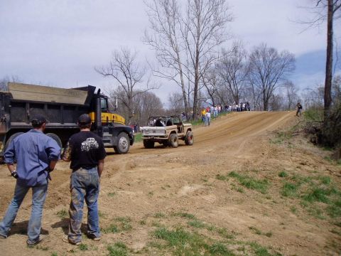1992 Ford Bronco - A group of people watch as off-road vehicles navigate a dirt track.
