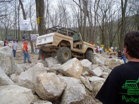 1992 Ford Bronco - A tan 1992 Ford Bronco tackles a challenging rocky terrain during an off-road event.