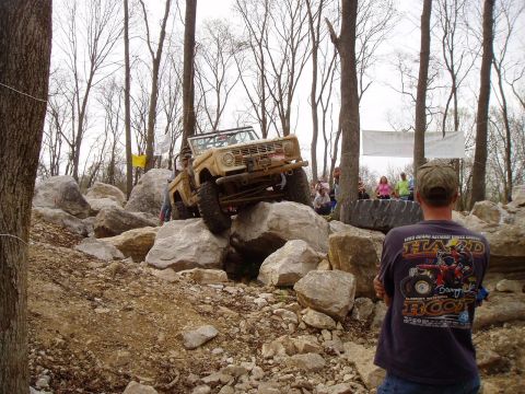 1992 Ford Bronco - A tan Ford Bronco navigates a challenging rocky terrain during an off-road event.