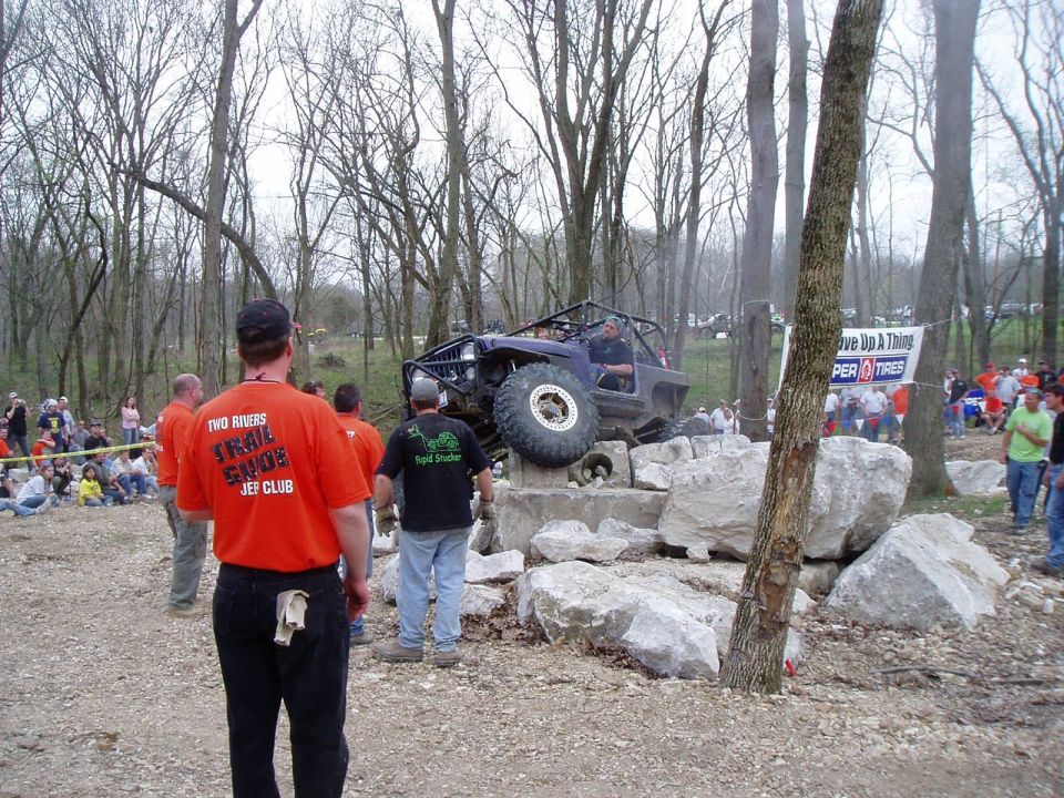 Off-road vehicle on rocks with spectators watching