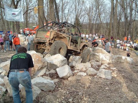 1992 Ford Bronco - An off-road vehicle attempts to conquer a challenging rock obstacle course with spectators observing the action.