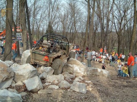 1992 Ford Bronco - Off-road vehicle attempts to navigate a rocky obstacle course with a crowd watching.