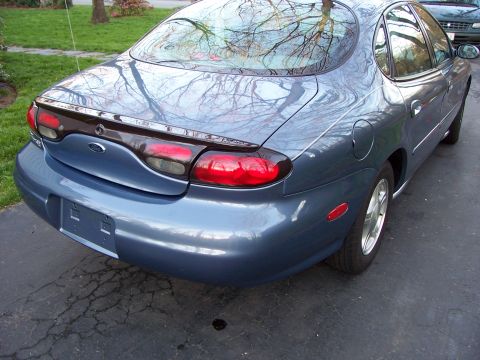 1999 Ford Taurus - Rear view of a blue 1999 Ford Taurus sedan, showing taillights and trunk area.