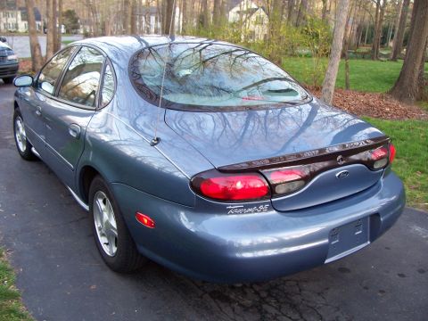 1999 Ford Taurus - The rear of a blue 1999 Ford Taurus SE sedan is visible from a 3/4 angle.