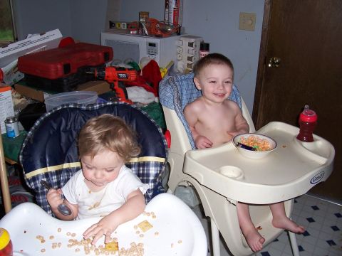 1983 Ford Bronco - Two young children are seated in high chairs and eating their meals in a messy indoor setting.