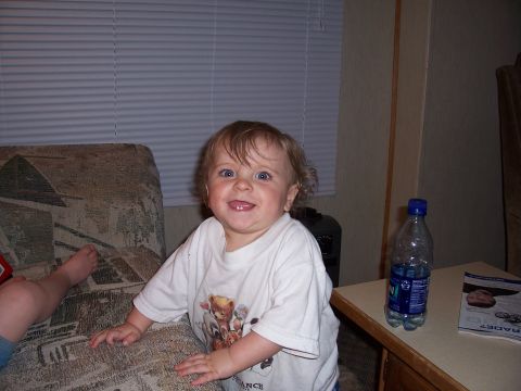 1983 Ford Bronco - A young child smiles while sitting on a couch, with a water bottle and magazine visible on a nearby table.
