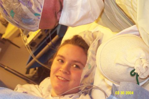 1983 Ford Bronco - A woman lies in a hospital bed, looking towards the camera with a smile, surrounded by medical equipment and blankets.