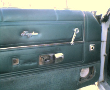 1977 Ford Ranchero - Close-up of a vintage car's interior door panel, a chrome window crank and door handle.