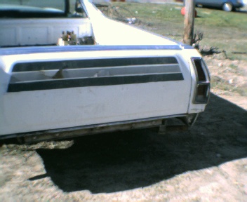 1977 Ford Ranchero - Rear view of a white 1977 Ford Ranchero showing its tailgate and a watermark.