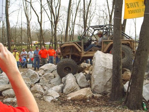1992 Ford Bronco - A heavily modified off-road vehicle tackles a challenging course with spectators watching.