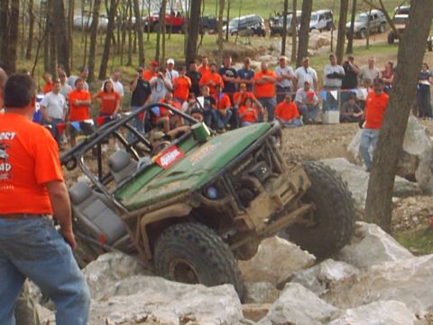 1992 Ford Bronco - An off-road vehicle tackles a rocky obstacle course with a crowd of spectators observing the event.