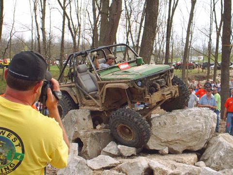 1992 Ford Bronco - A modified off-road vehicle navigates a challenging rock obstacle course with spectators watching.