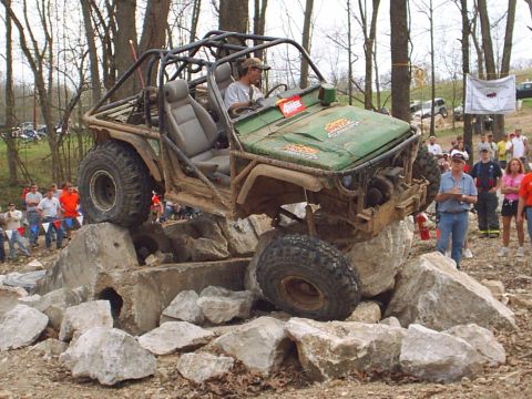 1992 Ford Bronco - An off-road vehicle navigates a challenging rocky obstacle course with spectators watching.