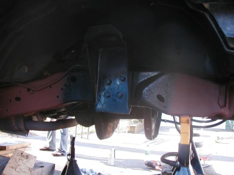 1994 Ford Bronco - The underside of a vehicle is shown with its frame and suspension components visible, supported by jack stands.