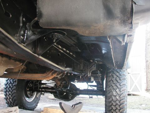 1994 Ford Bronco - A low-angle view shows the undercarriage of a vehicle, highlighting its robust frame and large tires, suggesting off-road capability.