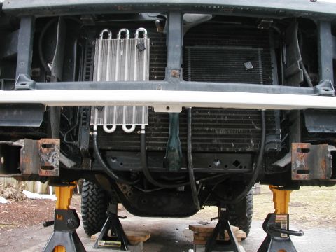 1994 Ford Bronco - The front end of a 1990s Ford Bronco is shown on jack stands, revealing its radiator and an added transmission cooler.