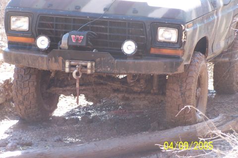 1979 Ford Bronco - Muddy 1979 Ford Bronco navigating rough terrain, equipped with a winch and aggressive off-road tires.