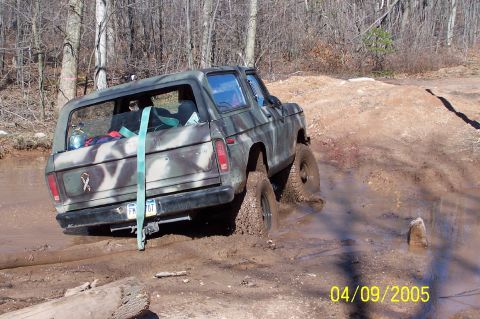 1979 Ford Bronco - This Ford Bronco is navigating a muddy off-road trail, kicking up dirt and water.