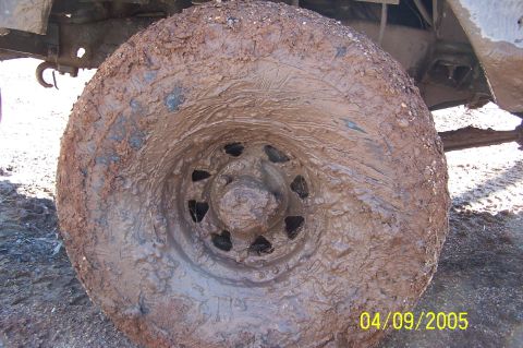 1979 Ford Bronco - A close-up view of a heavily mud-covered tire and wheel, obscuring any identifying details.