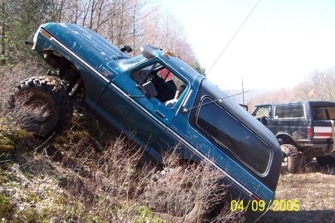 1979 Ford Bronco - This 1979 Ford Bronco is navigating a steep, wooded incline, with another SUV visible in the background.