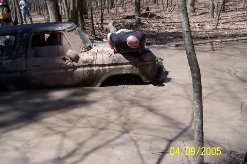 1979 Ford Bronco - A man attempts to free a heavily mud-covered truck stuck in a muddy body of water.
