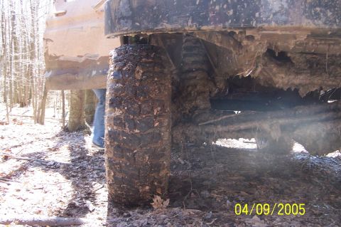 1979 Ford Bronco - A close-up view of a heavily soiled vehicle's undercarriage and tire, partially obscured by mud and debris.