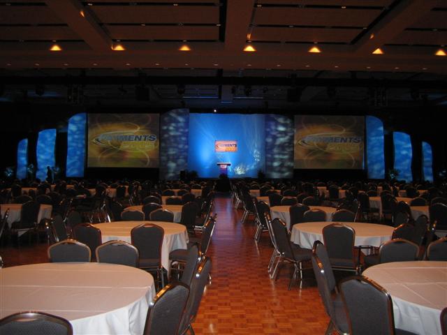 Conference hall with round tables and a stage displaying "Comments"