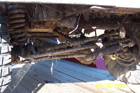 1979 Ford Bronco - Undercarriage of a heavily used off-road vehicle, covered in mud and dirt.