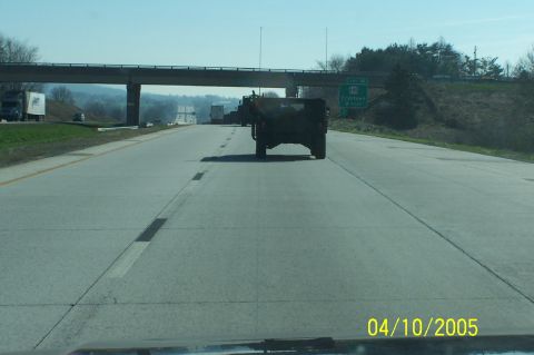 1979 Ford Bronco - A dark SUV drives on a highway under an overpass, with other vehicles visible.