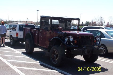 1979 Ford Bronco - A maroon pickup truck with a black roof and bed is parked in a lot next to other vehicles.