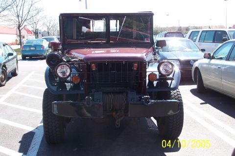 1979 Ford Bronco - Maroon military truck parked in a lot with other vehicles visible.