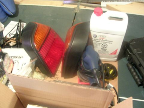 1990 Volkswagen Corrado - Car parts, including taillights and a jug of coolant, are laid out on a surface.