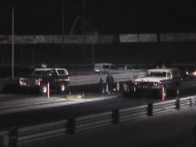 Dark SUVs at a drag race at night