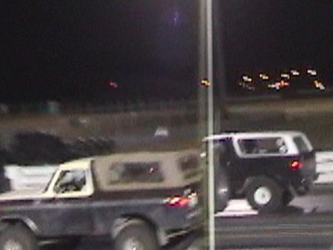 1978 Ford Bronco - Two SUVs are seen racing on a track at night, with lights visible in the background.
