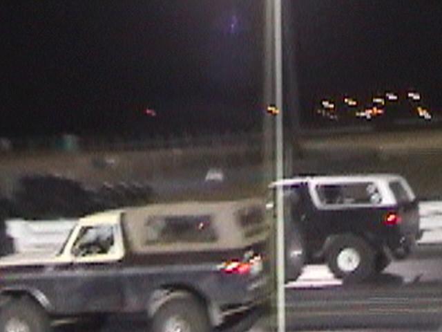 Two SUVs, one dark and one two-tone, race on a track at night
