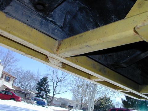 1979 Ford Bronco - Undercarriage of a vehicle, showing frame rails and undercoating, with a snowy residential background.