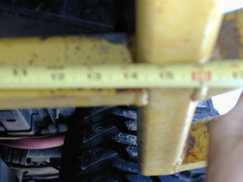 1979 Ford Bronco - A close-up view of a yellow metal frame and a tire, with a tape measure indicating measurements.