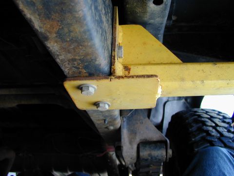 1979 Ford Bronco - Close-up of the undercarriage showing a yellow bracket bolted to the frame, with a tire in the background.