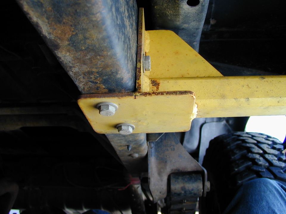 Undercarriage view of yellow bracket attached to frame, with tire visible