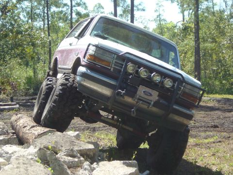1993 Ford Bronco - This modified Ford Bronco is navigating a challenging off-road course with large tires and a lifted suspension.