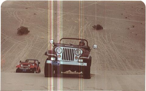 1995 Ford Bronco - Two Jeeps navigate sandy terrain, leaving tire tracks in their wake.