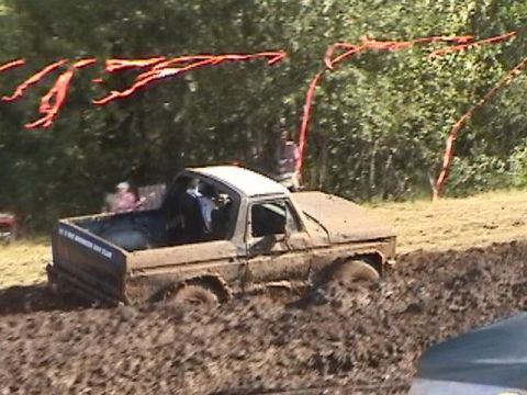 1978 Ford Bronco - A mud-covered pickup truck is stuck in a mud pit during a drag race event.
