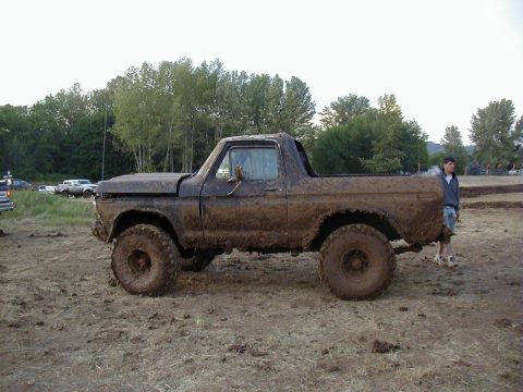 1978 Ford Bronco - This heavily muddied SUV is parked in a dirt area, likely after off-road activity.