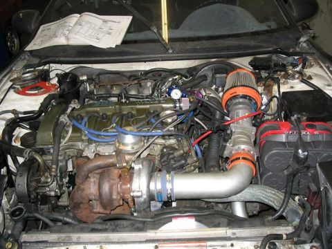 1993 Ford Probe - Engine bay modifications are visible, including a turbocharger and custom piping, with a manual open on the dashboard.